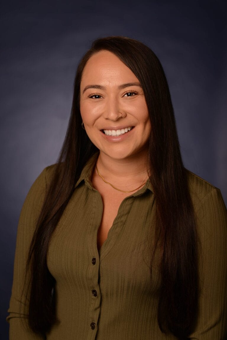 Professional business headshot of Natalie Mendez, smiling in an olive-green shirt.